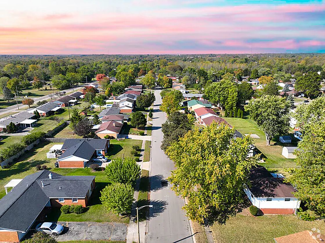 An aerial view of a tree-lined Dayton residential street at sunset